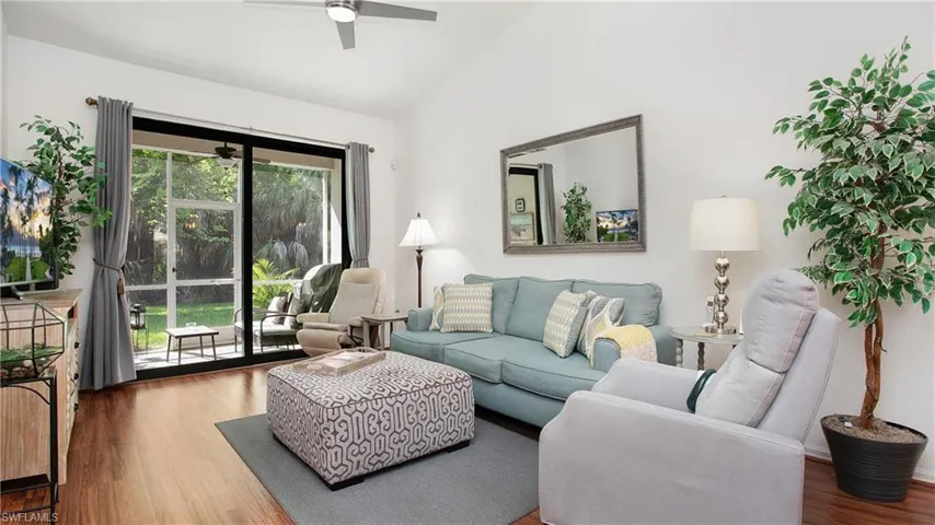 Living room featuring vaulted ceiling, wood finished floors, and a ceiling fan