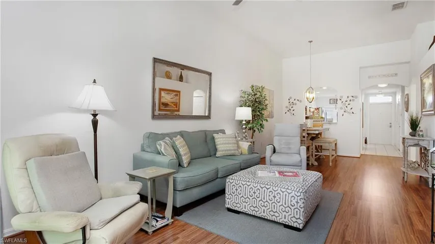 Living room featuring arched walkways, wood finished floors, and a towering ceiling