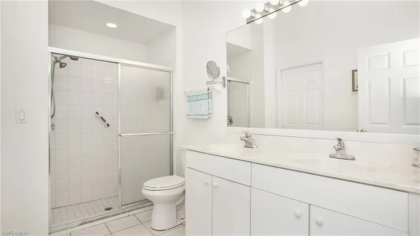 Bathroom featuring double vanity, a shower stall, and tile patterned floors