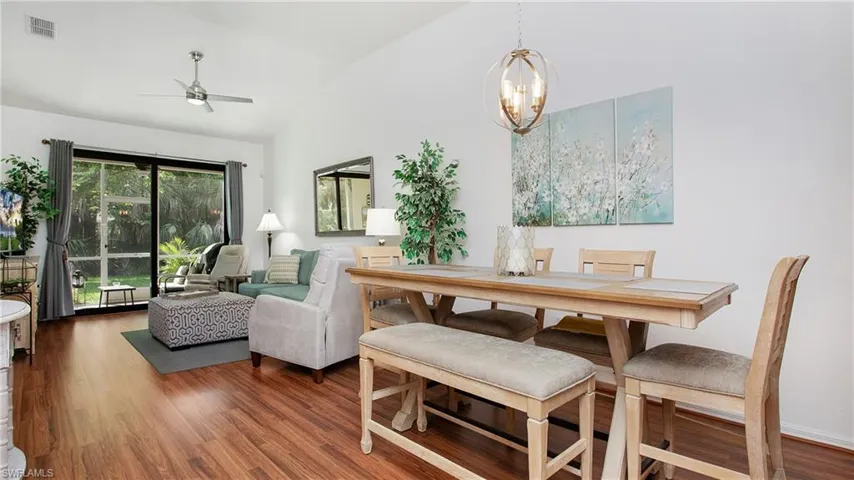 Dining area featuring a ceiling fan, a chandelier, wood finished floors, and high vaulted ceiling