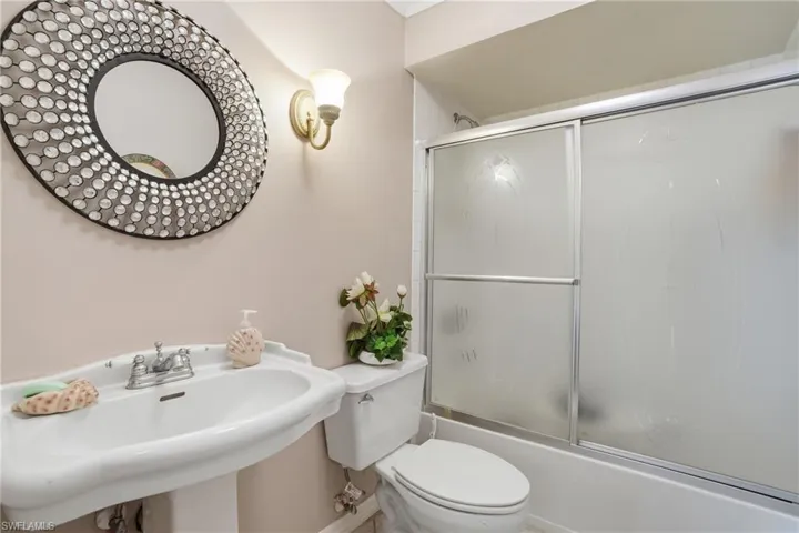 Bathroom with toilet and bath / shower combo with glass door