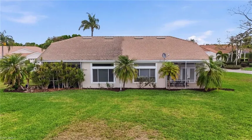 Rear view of property with a tiled roof, a sunroom, a yard, and stucco siding