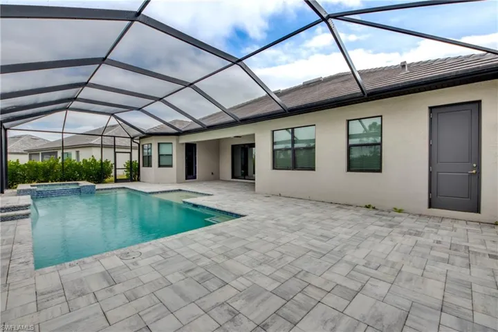 View of swimming pool featuring a sunroom, a pool with connected hot tub, glass enclosure, and a patio