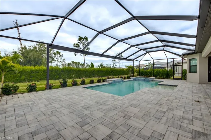 View of pool with a sunroom, glass enclosure, a pool with connected hot tub, and a patio