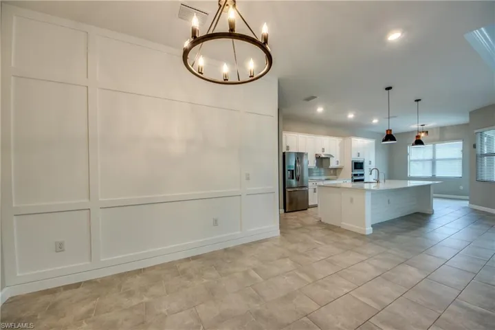 Kitchen with appliances with stainless steel finishes, a kitchen island with sink, a breakfast bar area, white cabinets, and recessed lighting