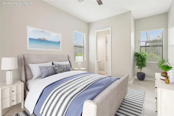 Bedroom featuring light tile patterned floors, ceiling fan, and ensuite bath