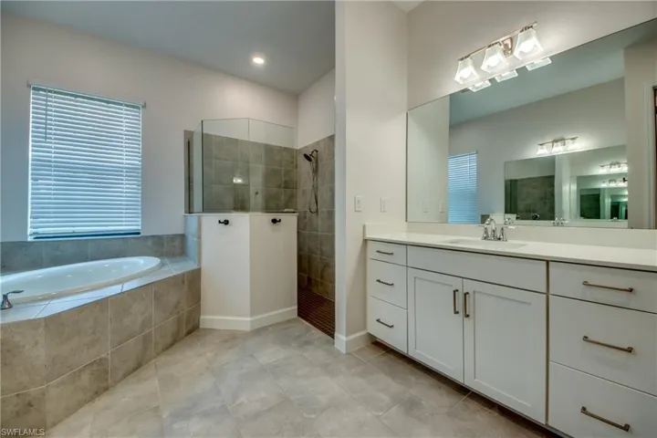Full bathroom featuring vanity, walk in shower, a garden tub, and light tile patterned floors
