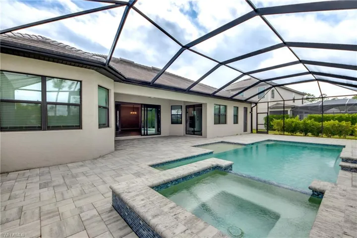 View of pool featuring a sunroom, a pool with connected hot tub, a patio area, and a lanai
