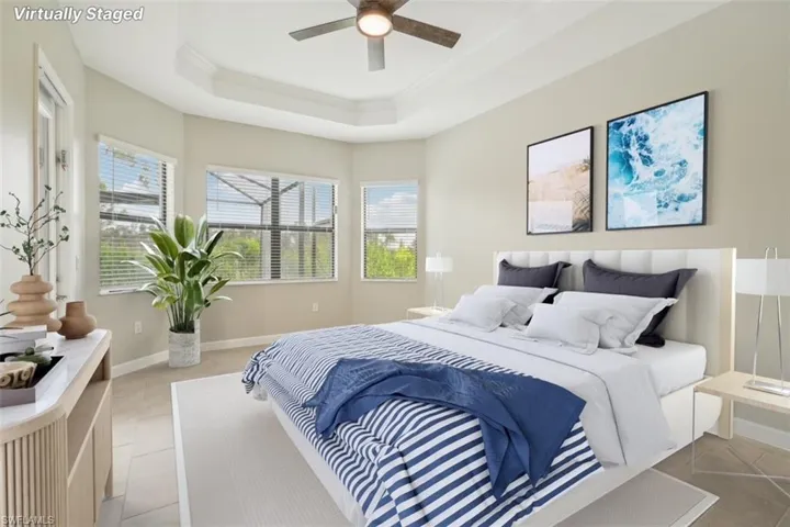 Bedroom with crown molding, a raised ceiling, light tile patterned floors, and ceiling fan
