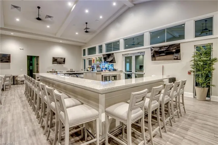 Community bar area with beamed ceiling, high vaulted ceiling, light stone countertops, ceiling fan, and recessed lighting