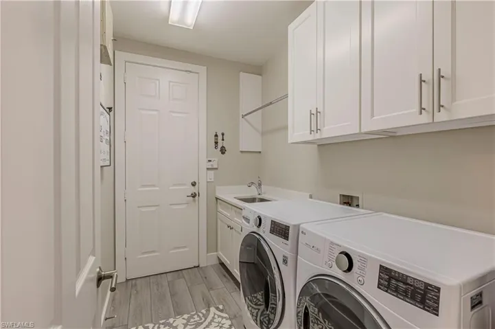 Laundry room featuring light wood-style flooring, cabinet space, and washing machine and dryer