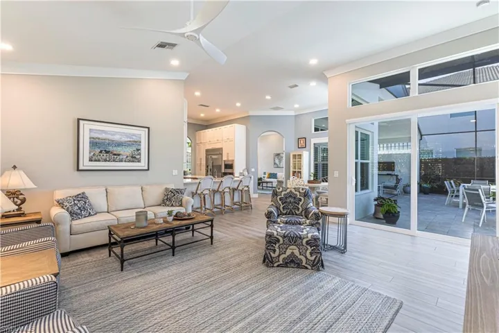 Living area featuring ceiling fan, crown molding, recessed lighting, light wood-style flooring, and arched walkways