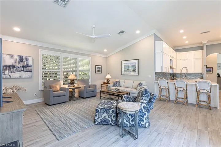 Living area featuring ornamental molding, a ceiling fan, light wood-style floors, arched walkways, and recessed lighting