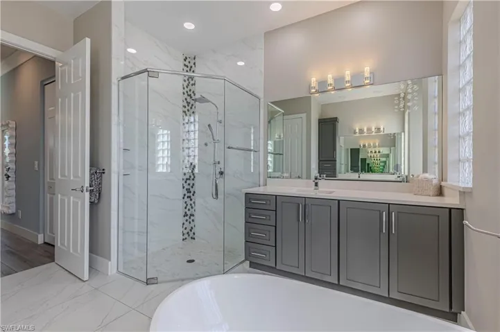 Full bathroom with a bathtub, vanity, a marble finish shower, baseboards, and recessed lighting