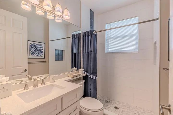 Bathroom with toilet, a tile shower, and vanity