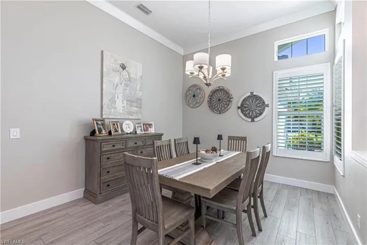Dining area with a chandelier, ornamental molding, light wood-style floors, and baseboards