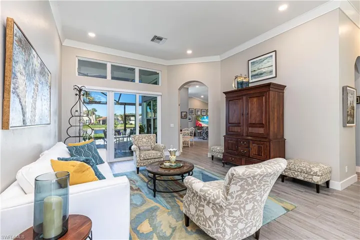 Living area with arched walkways, light wood-type flooring, ornamental molding, recessed lighting, and baseboards