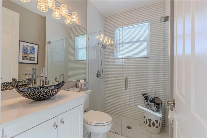 Bathroom featuring vanity, a shower stall, and toilet