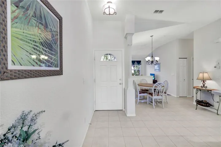 Foyer entrance featuring a chandelier, light tile patterned floors, and vaulted ceiling