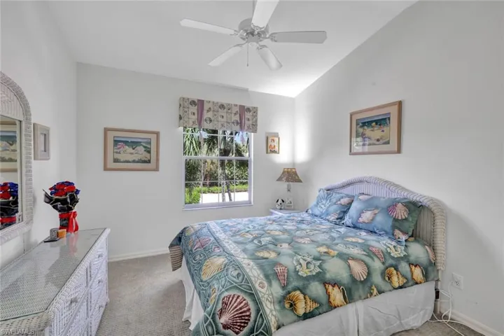 Bedroom with light carpet, a ceiling fan, and vaulted ceiling