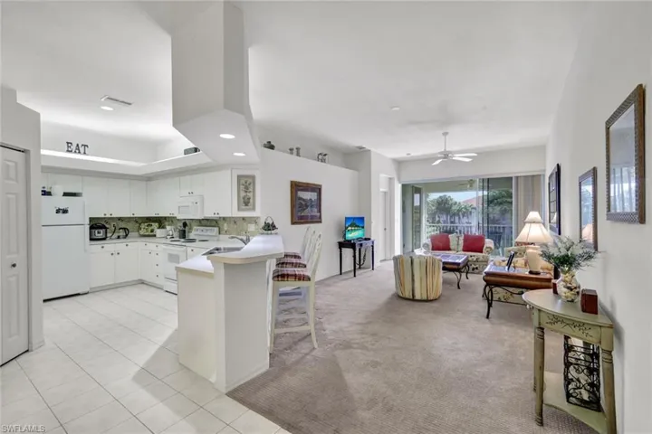 Kitchen with a peninsula, white cabinetry, white appliances, light colored carpet, and light countertops