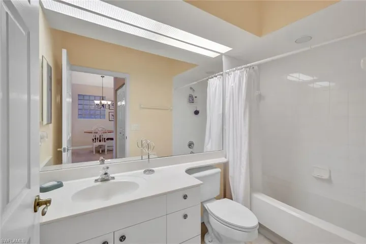 Bathroom featuring vanity, shower / bath combo, and a chandelier