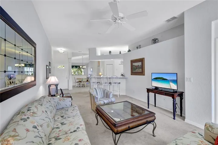 Carpeted living room with a ceiling fan and baseboards