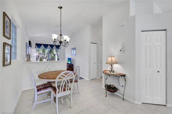 Tiled dining space featuring lofted ceiling and a chandelier
