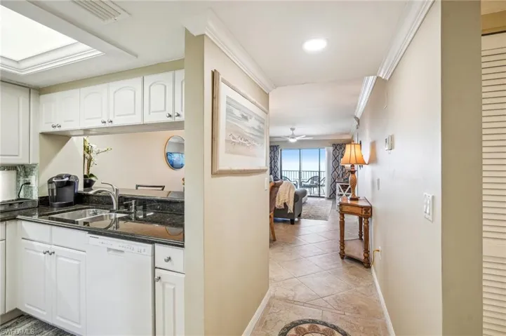 Kitchen featuring ceiling fan, sink, white dishwasher, white cabinets, and ornamental molding