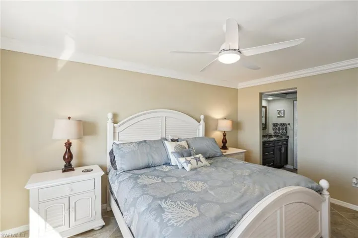 Bedroom with ceiling fan, light tile patterned flooring, and crown molding