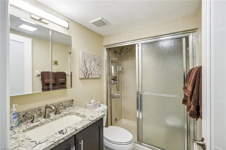 Bathroom with toilet, an enclosed shower, and vanity