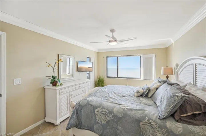 Bedroom featuring light tile patterned floors, ceiling fan, and crown molding