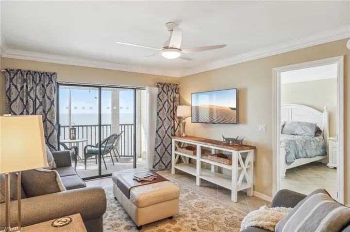 Living room with light tile patterned floors, ceiling fan, and crown molding