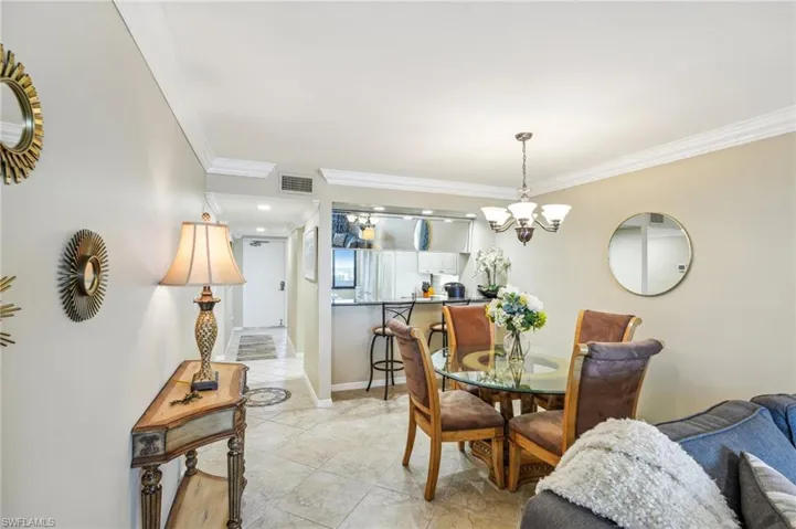 Dining area featuring crown molding, light tile patterned flooring, and a notable chandelier