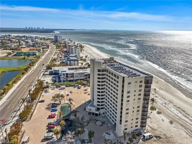 Birds eye view of property featuring a water view and a view of the beach