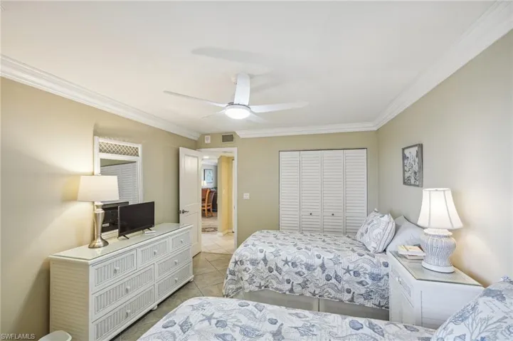 Tiled bedroom featuring ceiling fan, crown molding, and a closet