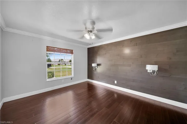 Spare room featuring ornamental molding, ceiling fan, wooden walls, dark wood-style flooring, and a textured ceiling