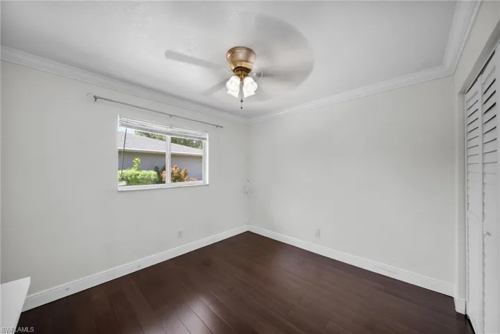 Unfurnished bedroom featuring ornamental molding, dark wood finished floors, a closet, and ceiling fan