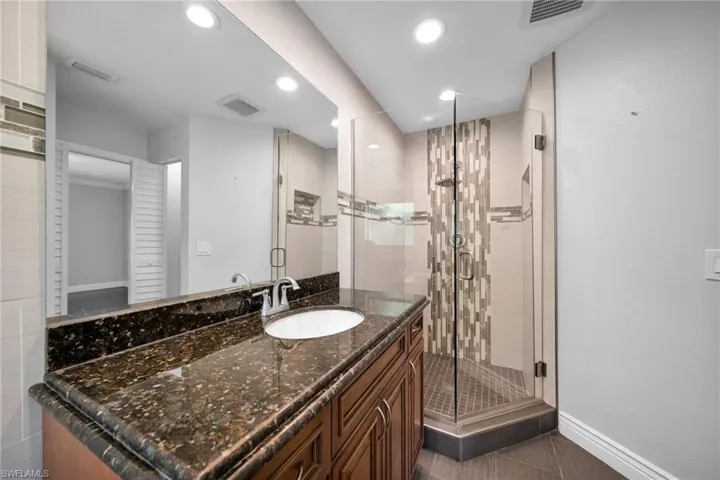 Full bathroom featuring vanity, a stall shower, recessed lighting, and dark tile patterned floors
