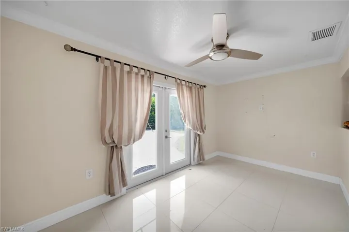 Tiled empty room with crown molding, french doors, and ceiling fan