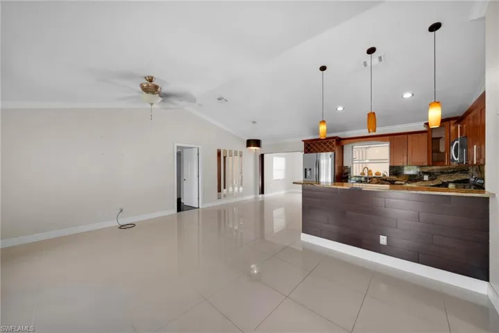 Kitchen featuring pendant lighting, light tile patterned floors, glass insert cabinets, decorative backsplash, and crown molding