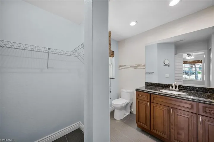 Full bathroom with vanity, a walk in closet, and a ceiling fan