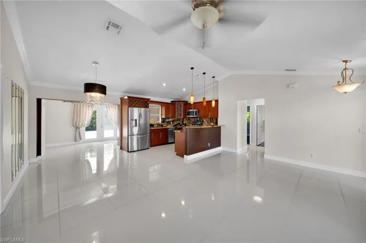 Kitchen featuring glass insert cabinets, vaulted ceiling, pendant lighting, tasteful backsplash, and a peninsula