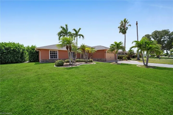 Single story home featuring stone siding, driveway, a front yard, and stucco siding
