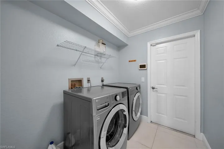 Laundry room featuring light tile patterned floors, crown molding, and separate washer and dryer