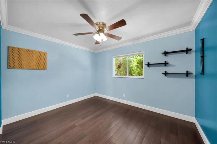 Spare room featuring ornamental molding, dark wood-type flooring, and a ceiling fan