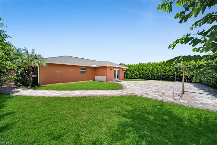 Rear view of property with a yard, stucco siding, driveway, and a patio