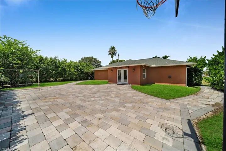 Back of house with a lawn, stucco siding, and french doors