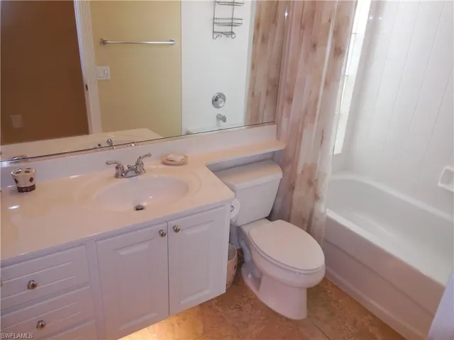 Full bathroom with shower / bathtub combination with curtain, vanity, tile patterned floors, and toilet