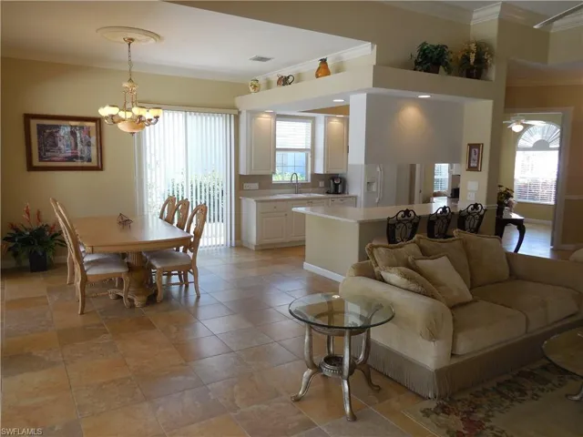 Tiled living room with a notable chandelier, sink, and crown molding